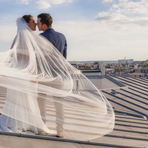 couple de mariés sur un toit avec tour eiffel et voile volant