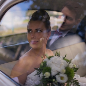 mariée dans une voiture qui regarde son mari qu'on voit dans le reflet de la vitre