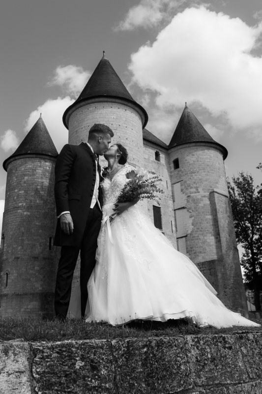 Photo des mariés s'embrassant devant un château