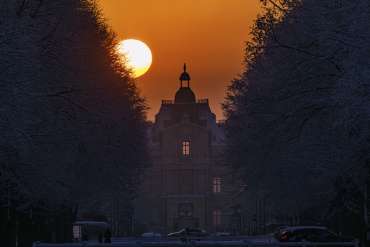 Soleil qui se lève derrière le château de Maisons-Laffitte enneigé.
