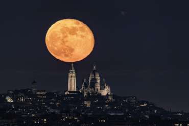 Pleine lune en bilboquet alignée avec la basilique du sacré-coeur dans le quartier de Montmartre à Paris.